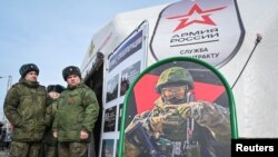 Руски војници стојат во близина на мобилен центар за регрутирање со постер со информации за плата во Ростов-на-Дон, Русија, март 2024 година