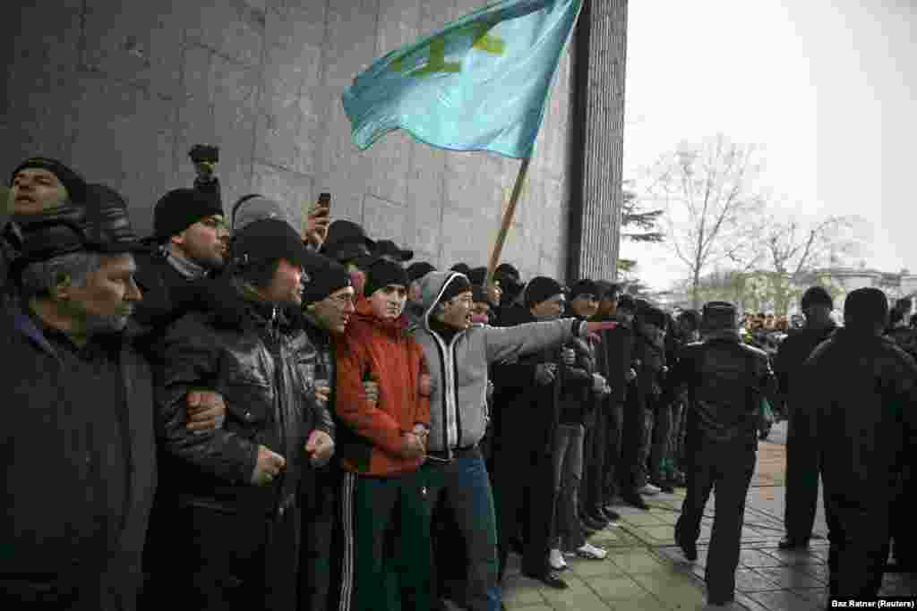 Крымские татары со своим флагом на митинге у парламента Крыма в Симферополе, 26 февраля 2014 года. Неделей ранее глава парламента Крыма поднял вопрос о возможности «отсоединения» полуострова от Украины. В это время в Киеве проходили массовые демонстрации с требованием отстранения от власти пророссийского президента Виктора Януковича, украинцы позже назвали эти события «революцией достоинства»