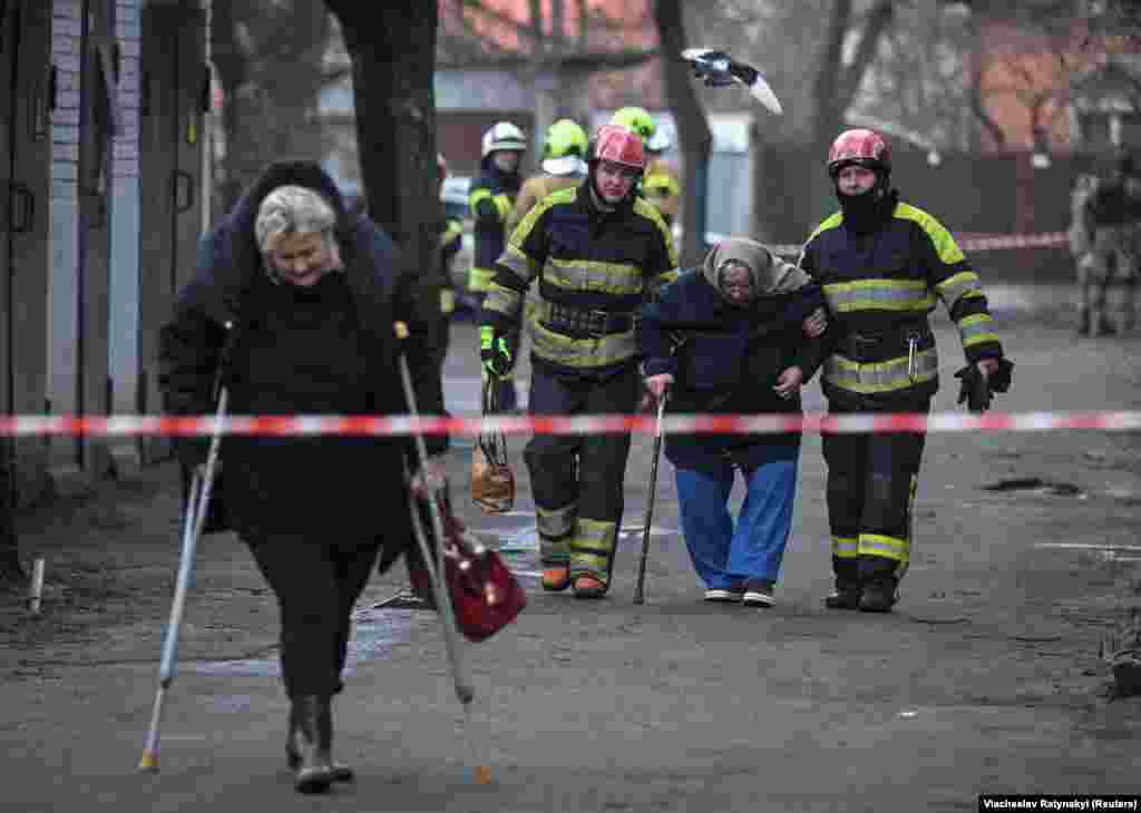 Ekipet emergjente duke ndihmuar banorët të largohen nga shtëpitë e tyre pas sulmeve me raketa.