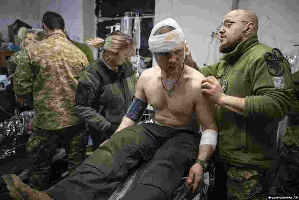Një mjek ushtarak ukrainas duke trajtuar shokun e tij të plagosur në spitalin fushor pranë Bahmutit, Ukrainë, më 26 shkurt 2023.