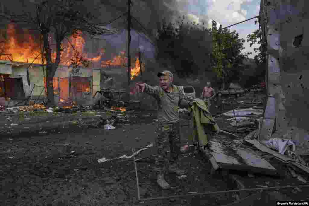 Украинский военнослужащий зовёт парамедиков. На земле лежат тела погибших и раненые в результате российской ракетной атаки на оживлённый рынок в центре Константиновки, 6 сентября 2023 года. Украинские официальные лица заявили, что жертвами нападения стали по меньшей мере 17 человек 