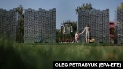Ljudi posjećuju spomenik žrtvama ratnih zločina u Buči, izvan Kijeva.
