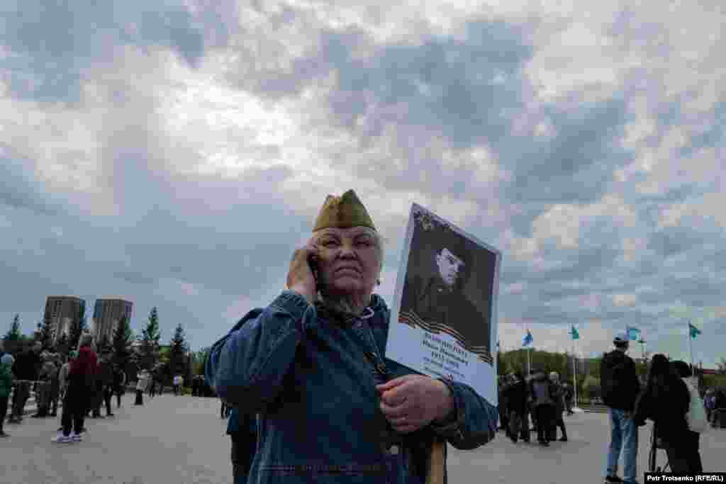 Екінші дүниежүзілік соғысқа қатысқан туысының фотосын ұстап тұрған әйел.