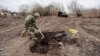 A Ukrainian serviceman buries the remains of what he said was the dead body of a Russian soldier in a village near Kyiv that was reclaimed by Ukraine in March 2022. 