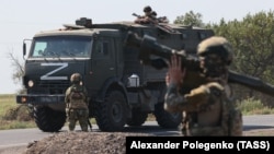 Russian soldiers guard a road as a Russian military convoy in Zaporizhzhya, Ukraine.