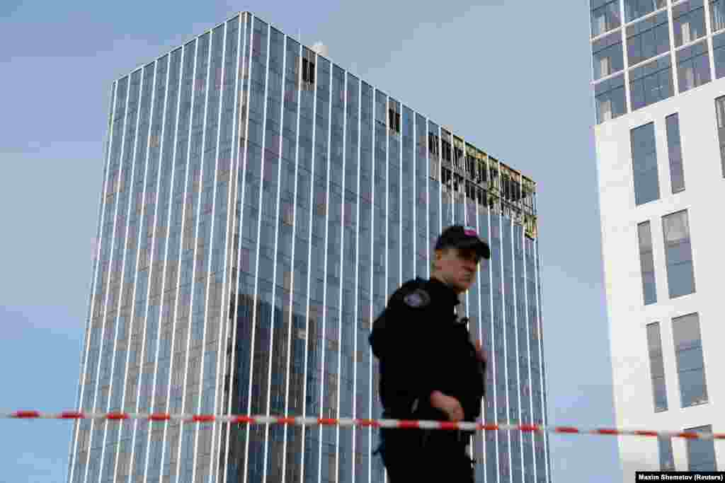 A member of the security services stands guard next to the site of a damaged building in Moscow. The TASS news agency reported one drone crashed in Komsomolsky Prospekt, near the ministry, while another hit a business center on Likhacheva Street by one of Moscow's main ring roads. 