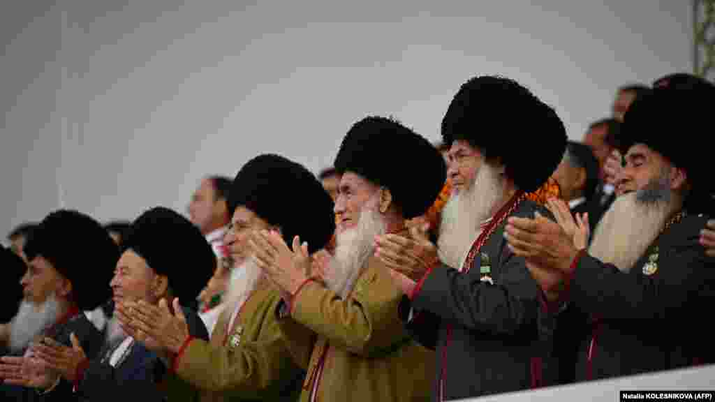 Аксакалы — мужчины-старейшины — аплодируют, наблюдая за празднеством с трибуны. И Бердымухамедов-старший, и его предшественник Сапармурат Ниязов построили культ личности, который включает тщательно продуманные подношения и памятники