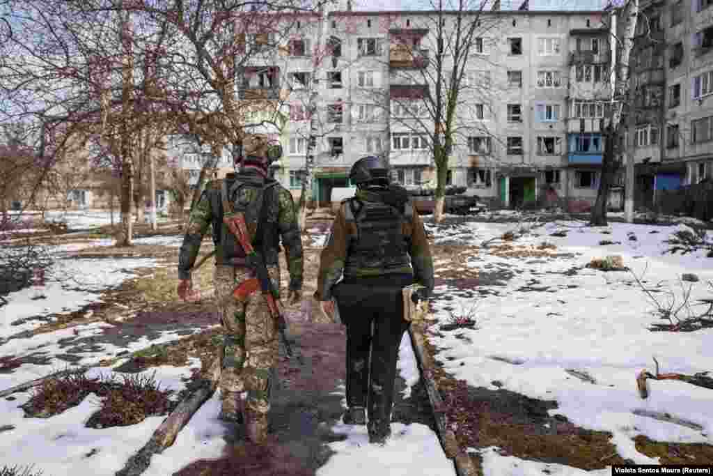 Un soldat ucrainean călăuzește un voluntar prin peisajul distrus din Ceasiv Iar în speranța că-i vor convinge pe ultimii rezistenți să evacueze localitatea. Se estimează că au mai rămas 1500 de locuitori, majoritatea dintre ei ducându-și zilele ascunși în subsoluri, fără electricitate sau apă curentă.