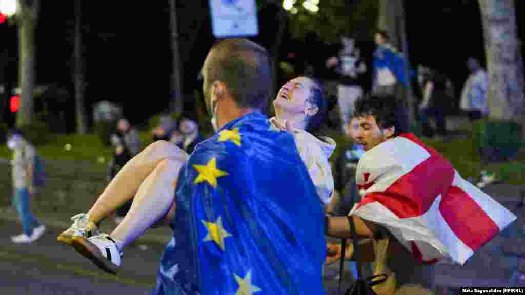 Një burrë i mbështjellë me një flamur të BE-së duke bartur një protestues të plagosur. Mbështetësit e projektligjit thonë se ai pasqyron legjislacionin e ngjashëm të SHBA-së dhe promovon transparencën. Ndërsa, kundërshtarët thonë se legjislacioni i propozuar do të mbyste mospajtimin dhe do të heshtte mediat e pavarura. Ata e kanë krahasuar atë me legjislacionin e ngjashëm në Rusi, prandaj shumë prej tyre e quajnë atë &quot;ligji rus&quot;.