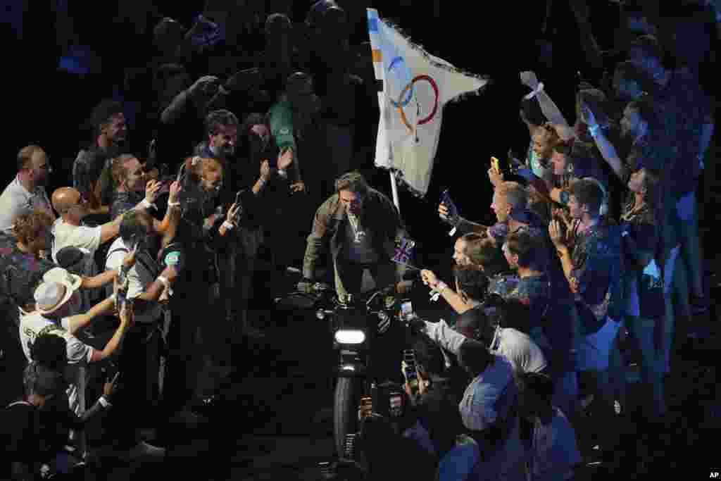 După ce preluat în mod simbolic steagul olimpic de la gimnasta americană Simone Biles, actorul Tom Cruise a ieșit din stadion pe motocicletă, a mers pe străzile Parisului către un aeroport și, într-o călătorie preînregistrată cu un avion militar, a sărit deasupra orașului Los Angeles. Organizatorii americani și-au propus ca, prin Jocurile Olimpice din 2028 de la Los Angeles, să limiteze traficul în oraș: locațiile olimpice ar urma să fie accesibile doar cu transportul public.