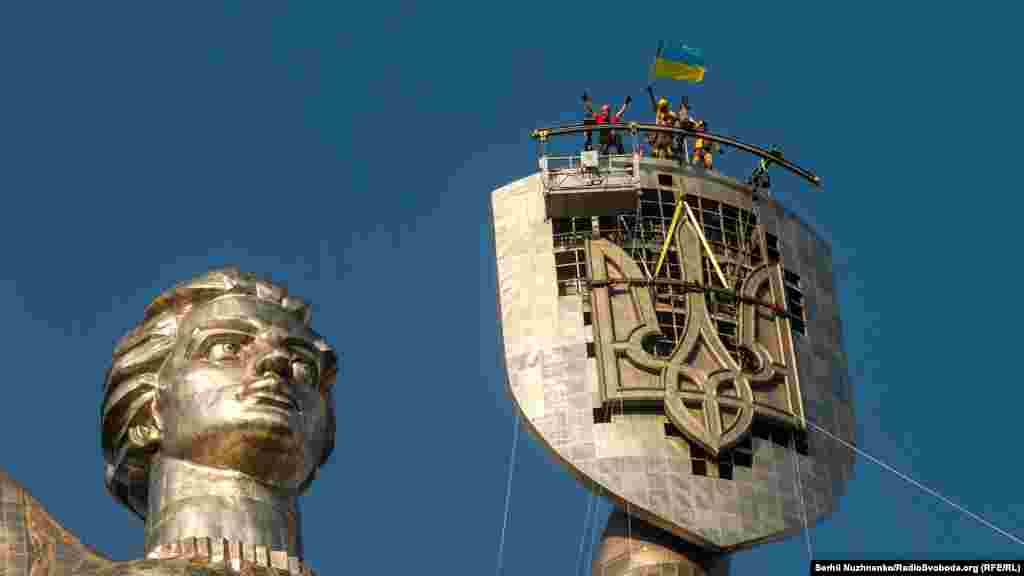 Рабочие отмечают установку украинского трезубца на щите монумента «Родина-мать» в Киеве, 6 августа 2023 года. Огромный трезубец заменил советский герб