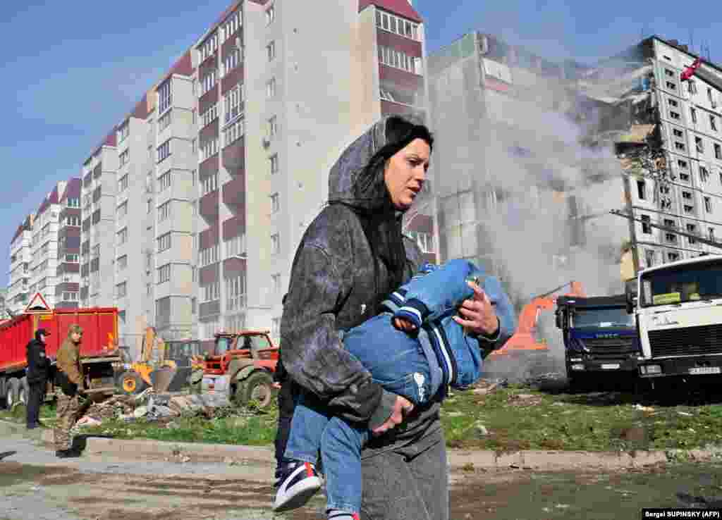 28 aprilie 2023, Uman: O femeie și copilul său trec pe lângă o clădire bombardată în acea noapte.
