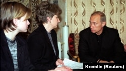 Russian President Vladimir Putin (right) talks with Irina Lyachin, the wife of the commander of the Kursk submarine, and her daughter in their flat in the naval town of Vidyayevo on August 22, 2000.