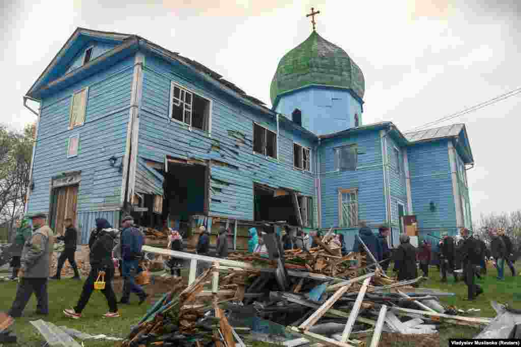 Локални жители ја напуштаат православната велигденска богослужба во црквата „Рождество на Пресвета Богородица“, која беше оштетена од гранатирање во селото Перемоха.