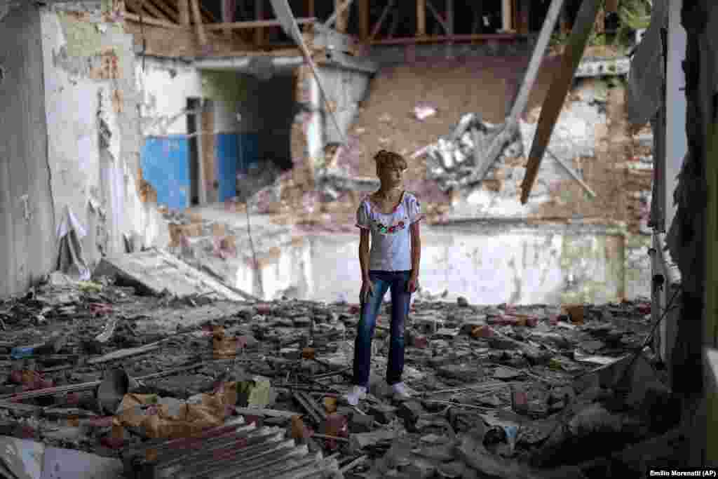 Sofia Klîșnia (12 ani) este surprinsă printre dărâmăturile fostei sale săli de clasă, în același loc în care se afla odinioară banca ei. „Este înfricoșător să stau în partea distrusă a clasei în care cândva am învățat”, a spus ea.