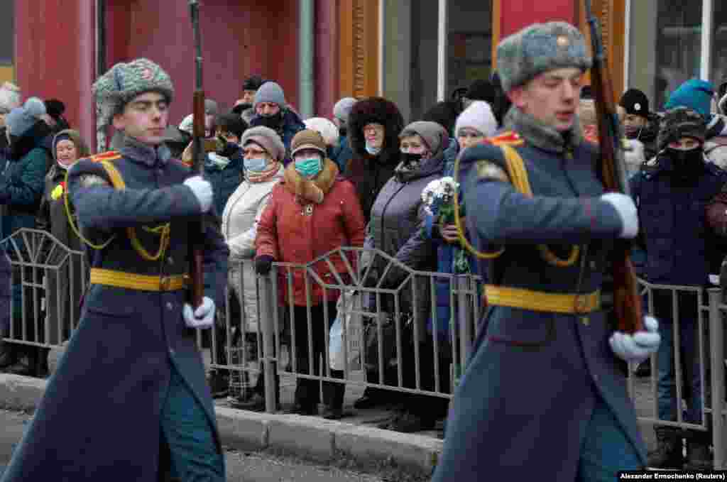 Местные жители в регионе под контролем так называемой "Донецкой народной республики" смотрят на почетный караул во время церемонии в память о попадании ракеты в троллейбус 7 лет назад, 22 января 2022