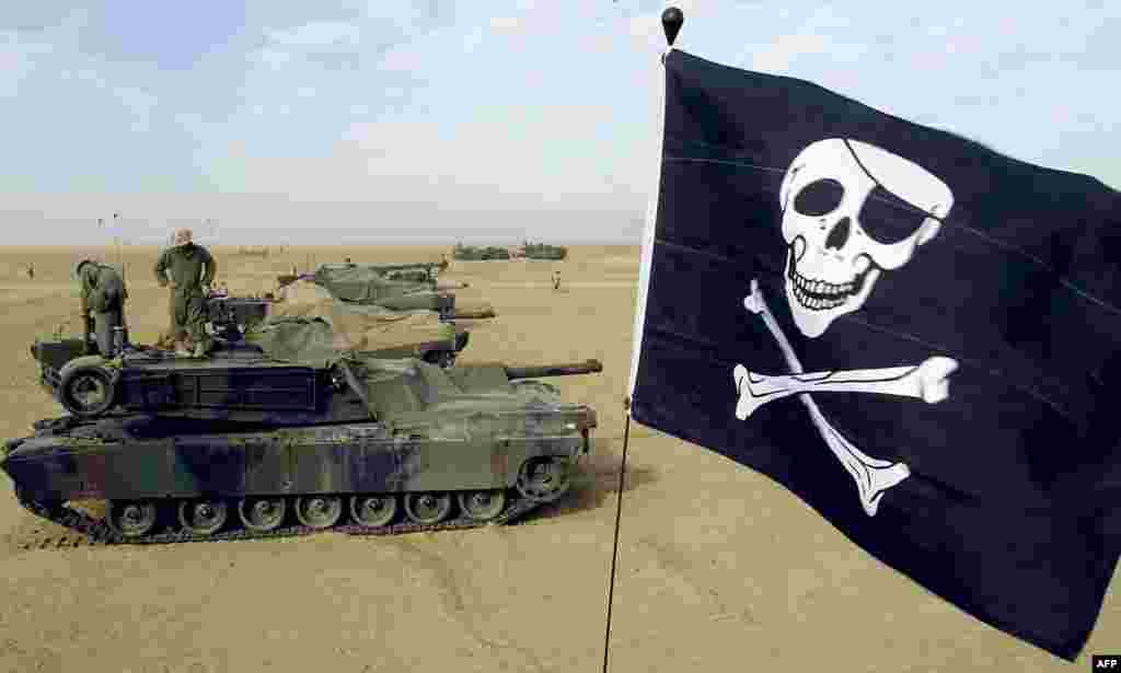 Резервисты Корпуса морской пехоты США на танке M1A1 «Абрамс» управляют «Веселым роджером» (пиратским чёрным флагом с черепом человека и костями). Лагерь морской пехоты США Гризли в Кувейте, 16 февраля 2003 года. Танк претерпел различные модернизации, в результате были созданы версии M1, M1A1 и M1A2. Улучшались вооружение, защита и электроника 