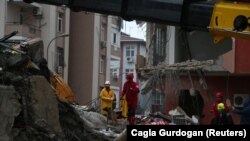 Член Поисково-спасательной ассоциации (AKUT) с собакой-ищейкой обыскивает выживших на месте обрушившегося здания после землетрясения в Адане, Турция, 6 февраля 2023 г.