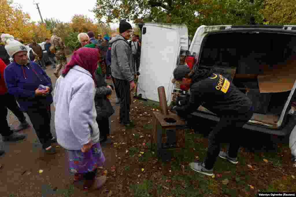 Un voluntar de la OperationAid distribuie sobe locuitorilor dintr-un sat din regiunea Nikolaev, la 25 octombrie. Ludvig Ramestam, unul dintre fondatorii organizației caritabile suedeze OperationAid, a declarat pentru RFE/RL că sobele devin tot mai importante în întreaga Ucraină, deoarece Rusia vizează infrastructura energetică. „Iarna se apropie și aș spune că abia acum, în octombrie, începem să vedem ce ne va aștepta în Ucraina", spune el. 