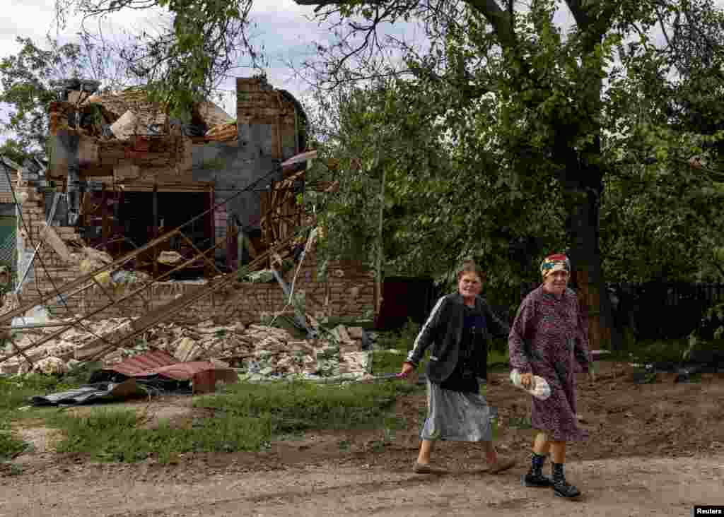 Ukrainian women take little notice of a destroyed house at a village in the Mykolayiv region.