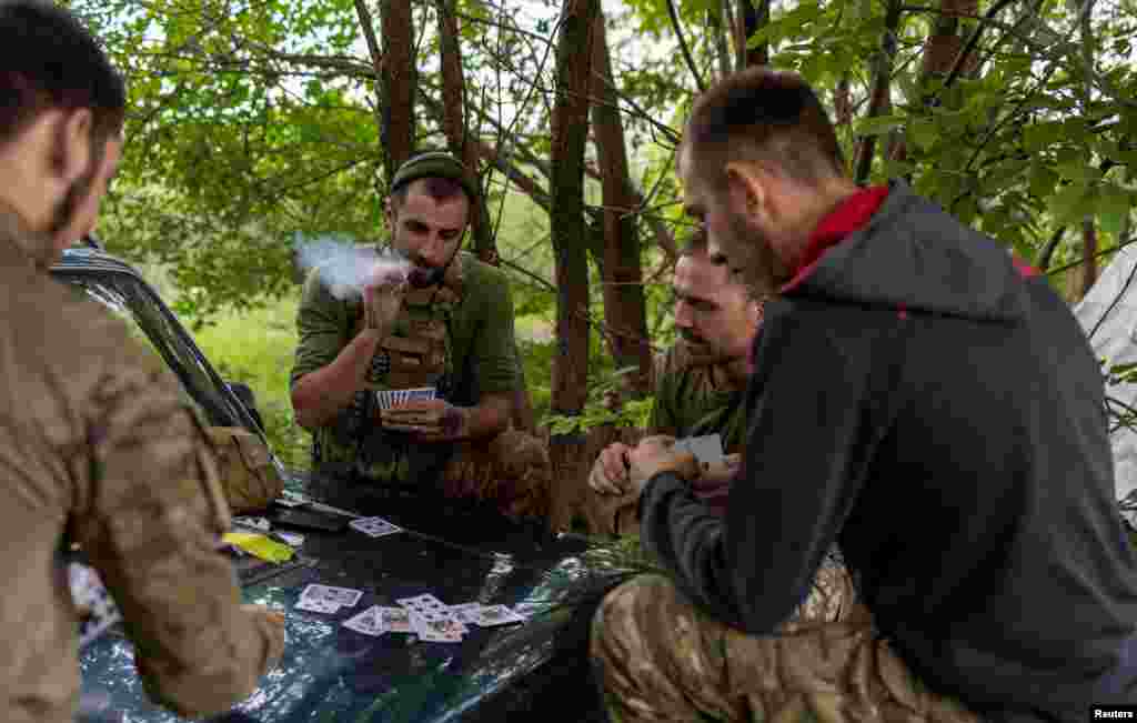 Ukrainian troops play cards to pass the time.