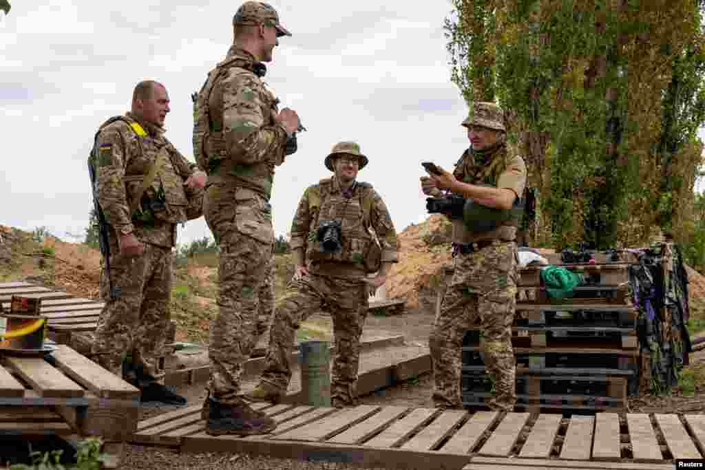 A newly recruited volunteer, Steve Andre, a 37-year-old from Detroit, Michigan, chats with his comrades while working as a photographer with a Ukrainian brigade at a position near a front line in the Mykolayiv region.