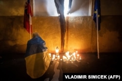 Një grua e veshur me një flamur ukrainas duke ndezur një qiri në kujtim të gazetarëve hulumtues të vrarë Jan Kuciak dhe Martina Kusnirova si reagim ndaj rezultateve të zgjedhjeve në Bratislavë më 1 tetor.