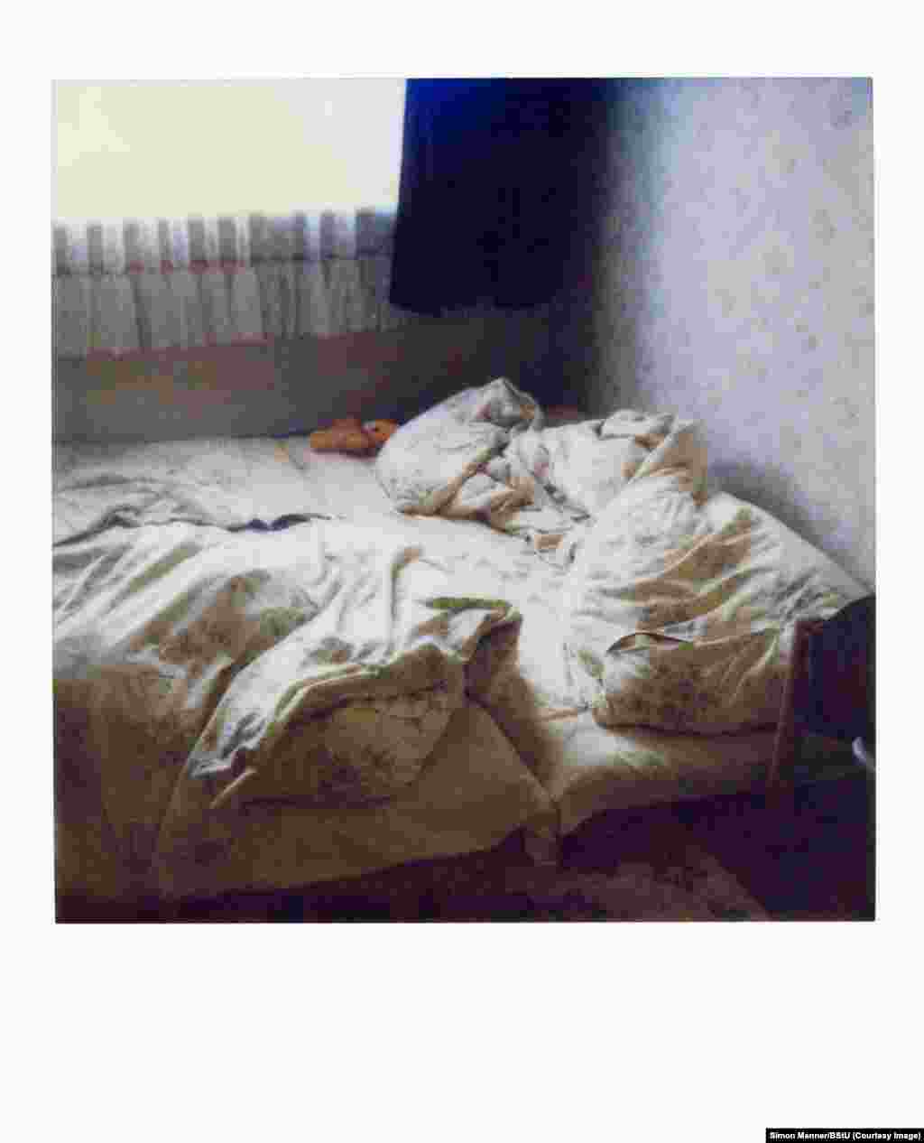 Поляроидная фотография кровати в пустой квартире. Такие фотографии часто делались во время проведения тайных обысков, чтобы агенты Штази могли оставить вещи после ухода в том же состоянии, в котором их оставил ничего не подозревающий жилец квартиры. 
