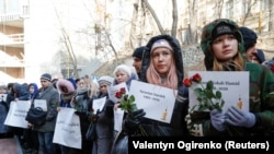 Emberek az Irán fölött lelőtt ukrán gép áldozatainak a neveivel emlékeznek meg a szerencsétlenségről Irán kijevi nagykövetségének az épülete előtt 2020. február 17-én.
