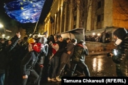 Протестующие движутся в сторону полицейского спецназа, прикрываясь щитом