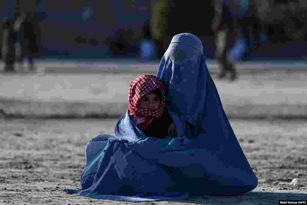 Një grua afgane e veshur me burka duke mbajtur një fëmijë, teksa kërkonte lëmoshë para Xhamisë së Madhe të Heratit.