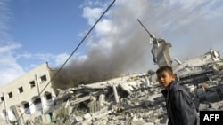 A Palestinian boy stands in front of a destroyed building in Gaza City on December 27