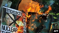 Protesters burn anti-North Korea placards with images of the North's leader, Kim Jong Il, during a protest in Seoul on May 25.