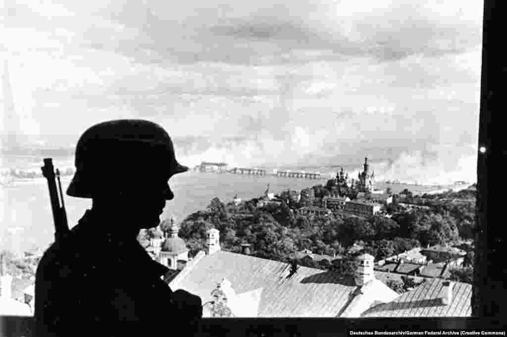 Германски войник в камбанарията на Великата Лавра в Киев през септември 1941 година. На заден план може да се види горящ мост над река Днепър.