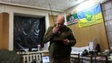 Украинский военнослужащий вблизи фронта на фоне флагов Ичкерии и батальона территориальной обороны. Иллюстративная фотография