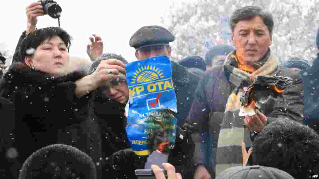 Лидеры оппозиции сжигают плакаты партии «Нур Отан» в рамках акции протеста против результатов парламентских выборов. Болат Абилов - первый справа. Алматы, 17 января 2012 года.
