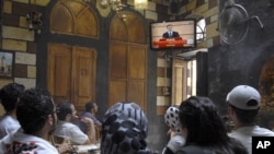 Syrians watch on television as President Bashar al-Assad delivers a speech on June 20.