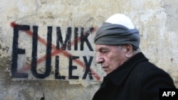 A Kosovar Albanian man walks in front of anti-EU and UN graffiti in the capital, Pristina, in late November.