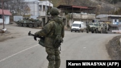 A Russian peacekeeper stands guard on a road in the town of Lachin on December 1, 2020.