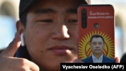 Президенттікке кандидат Садыр Жапаровтың суреті жапсырылған смартфон ұстап тұрған жігіт. Бішкек, Қырғызстан, 11 қаңтар 2021 жыл.