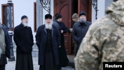 Ukrán rendfenntartók és ortodox papok a kijevi Pecserszk Lavra-monostor előtt 2022. november 22-én