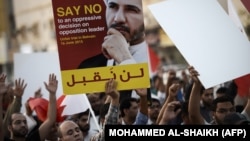 Bahraini protesters hold a placard portraying Sheikh Ali Salman, head of the Shiite opposition movement Al-Wefaq, during a demonstration against his arrest on June 16, 2015, in the village of Jidd Hafs, west of Manama.