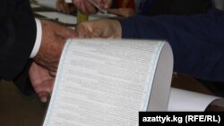 Кыргызстандын шайлоо тарыхында бул жолу эң узун (72 см.) бюллетен колдонулду.(Сүрөттө: Бишкектеги бир добушканада шайлоочуга бюллетен берилүүдө, 10-октябрь)