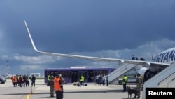 A reptéri személyzet és a biztonsági erők láthatók az aszfalton egy Ryanair-járat előtt, amely kénytelen leszállni Minszkben, 2021. május 23-án