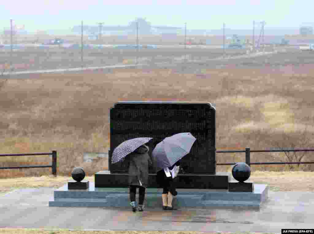 Këta persona nderojnë viktimat e tërmetit dhe cunamit në Fukushima, pranë kësaj pllake përkujtimore të vendosur në Namie më 11 mars, 2019.&nbsp; &nbsp;