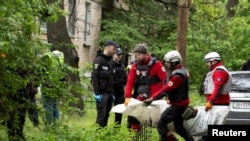 Lucrători de urgență ucraineni transportă trupul unei persoane care a murit când o dronă rusească a lovit o clădire de apartamente din Kiev, pe 7 mai.
