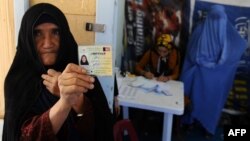 An elderly woman displays her identification card to vote in Afghanistan's forthcoming presidential election at a registration center in Herat.