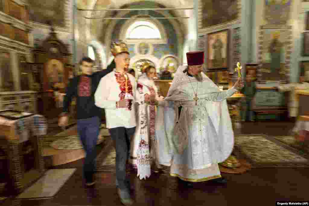 Ushtari ukrainas "Karp" dhe gruaja e tij, Anna, një vullnetare, udhëhiqen nga një prift gjatë ceremonisë së tyre martesore në rajonin e Harkivit më 24 korrik. Rritja masive e dasmave në Ukrainë ka precedent historik. Në kulmin e Luftës së Dytë Botërore në vitin 1942, Shtetet e Bashkuara regjistruan 1.8 milion dasma në 12 muaj - një rritje prej 83 për qind krahasuar me një dekadë më parë.