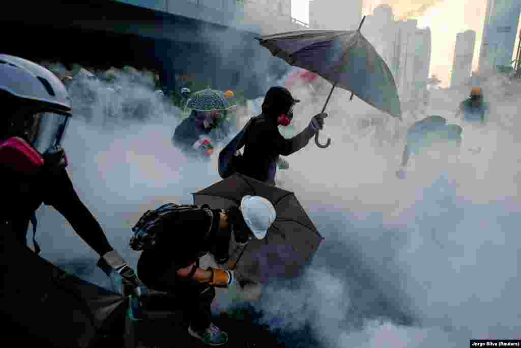 Protestatari care se apără sub umbrele de gazele lacrimogene în timpul demonstrațiilor de lângă guvernul din Hong Kong. 15 septembrie 2019. (Reuters/ Jorge Silva)