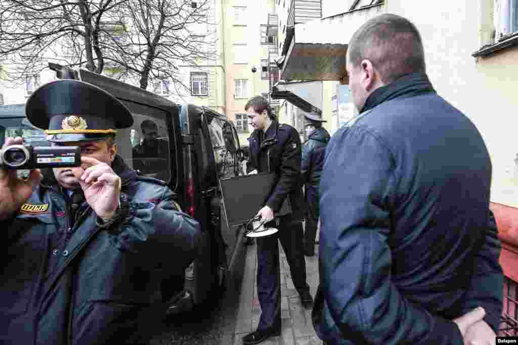 Милиция қызметкері тінту жүріп жатқан "Белсат" тәуелсіз телеарнасының Минскідегі кеңсесі жанына жиналған адамдарды видеоға түсіріп тұр.